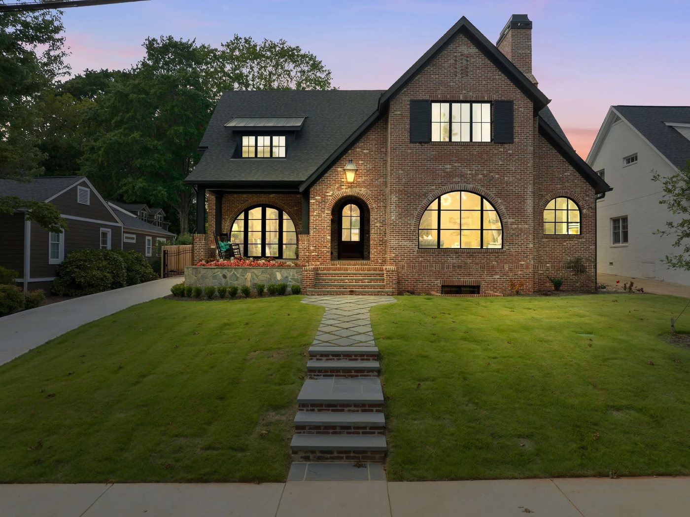 Brick Tudor-style home with black arched windows at dusk